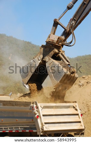 Clamshell bucket loader working a spoil pile on a hill removal project in Roseburg Oregon