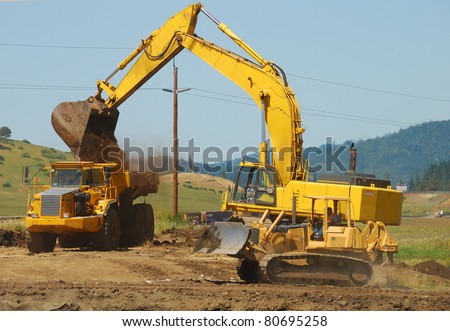 Large excavator loading a large dump truck at a new freeway interchange project near Roseburg Oregon