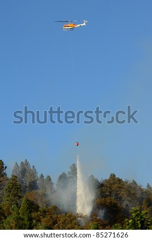 Large helicopter with a 500 gallon water bucket working a natural cover fire near Roseburg Oregon