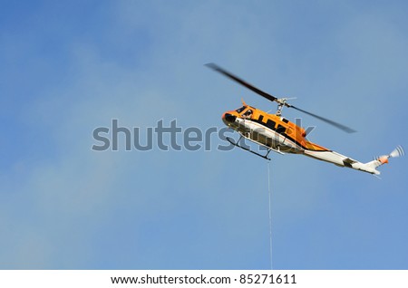 Large helicopter with a 500 gallon water bucket working a natural cover fire near Roseburg Oregon