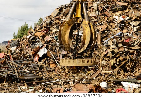Large tracked excavator working a steel pile at a metal recycle yard with a magnet.