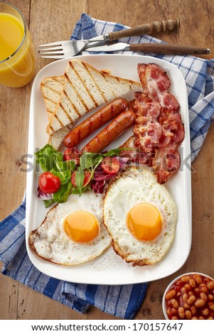 English Breakfast With Fried Eggs, Bacon, Sausages, Beans, Toasts And Fresh Salad