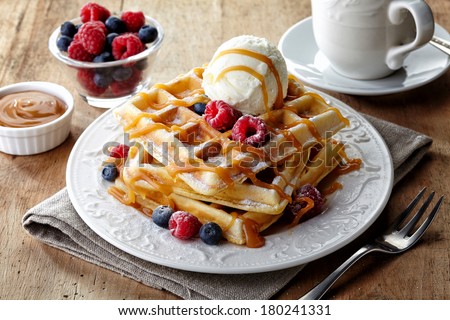 Plate of belgium waffles with ice cream, caramel sauce and fresh berries