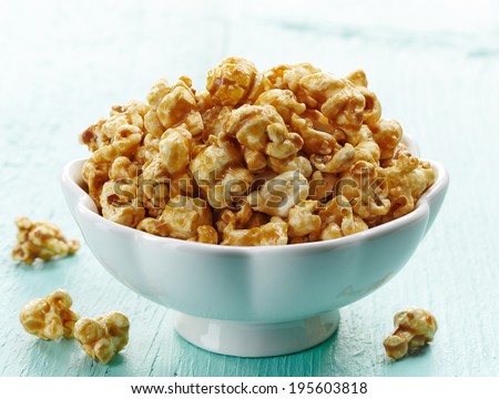 Bowl of sweet caramel popcorn on blue wooden background