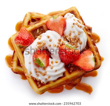 Belgian waffles with caramel sauce, whipped cream and strawberries isolated on white background (top view)