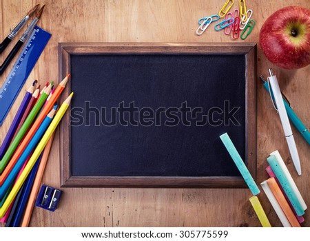 Blank chalkboard with school office supplies on wooden background. Back to school concept.