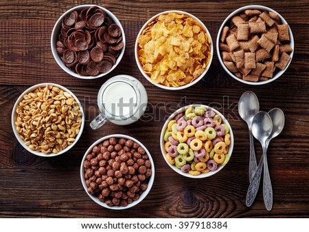 Bowls of various cereals and milk from top view