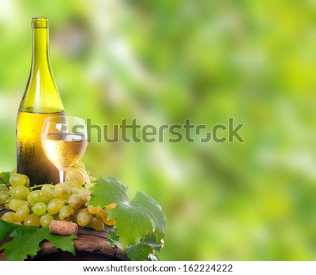 A bottle of wine and a glass of wine standing on an old wooden barrel. Against the background of the vine.