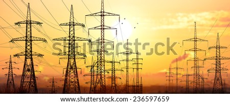 High-voltage power lines in an industrial area .On background sunrise.