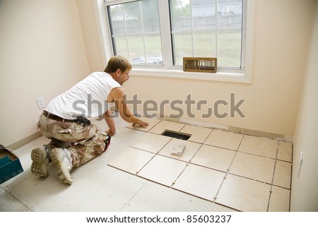 Man installing ceramic tile in customers kitchen, getting ready to sell home