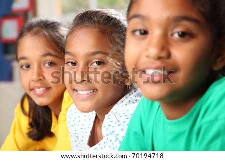 Row of three smiling young school girls sitting in class Row of three smiling young school girls sitting in class