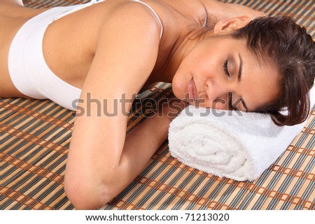 Beautiful woman lying face down in spa on towel