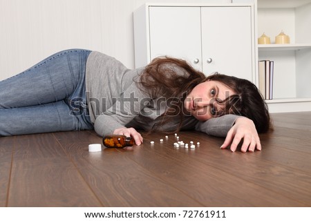 Teenage girl lying on the floor at home, alone with a blank expression on her face.