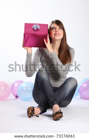 Happy birthday. Time to celebrate for beautiful young caucasian girl with long hair, sitting on the floor with a birthday present.