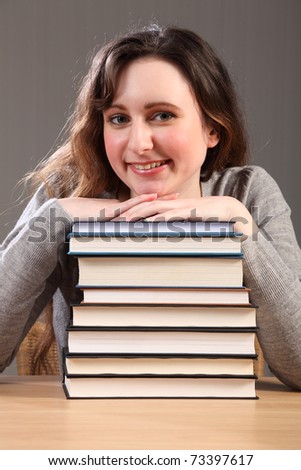 Time for a break for young caucasian student girl, sitting with big smile resting chin on stack of work books.
