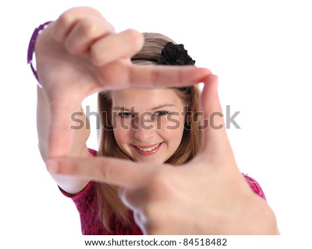Fun picture frame hand sign by pretty caucasian school girl with happy smile, wearing pink t-shirt with black flower hair band in her blonde hair.