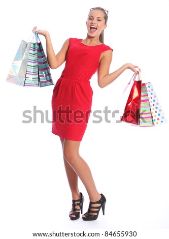 Shopping gift bags held by beautiful sexy young woman with lovely happy smile, wearing black high heeled shoes and short red dress. She has blond brown hair and sunglasses.