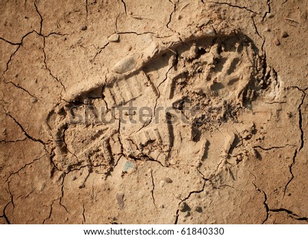 Imprint of the shoe on the dried and cracked mud. Closeup shot.