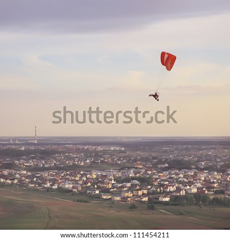 Paragliding over small suburban houses at early sunset