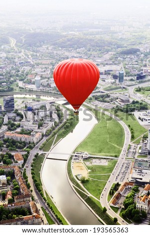Big red hot air balloon over city and river panorama