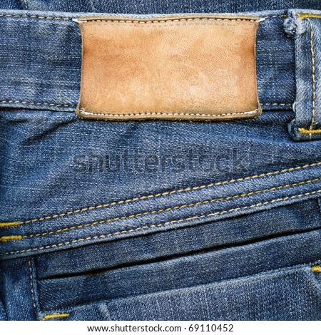 Highly detailed closeup of blank grungy stained leather label on old blue jeans with lot of seams, some kind of background