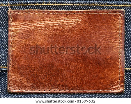 Highly detailed closeup of blank brown grungy leather label on denim, good for background
