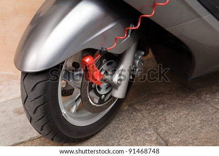 Red modern safety lock on parked motorbike wheel