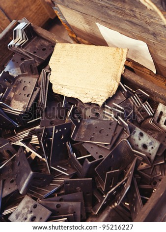A piece of messy cardboard as a background for your text placed on a pile of grungy metal details in a factory