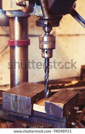 An old industrial electric heavy drill head in a factory for metal and wood drilling