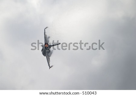 F-16 jet in a hard banking turn with afterburner lit.  Vapor clouds forming over the wings as it rips through the air
