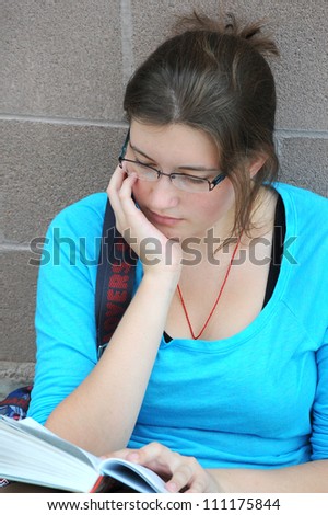 Female student reading a book outside.