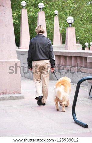 Female dog walker walking a dog outside.