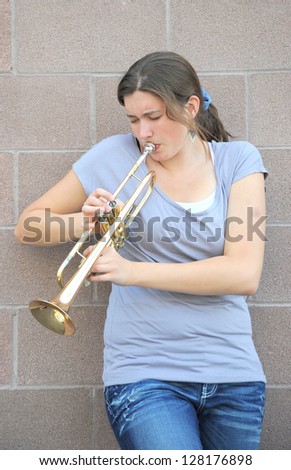 Female trumpet player blowing her horn outside.