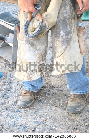 Male farrier working on a horseshoe at the ranch.