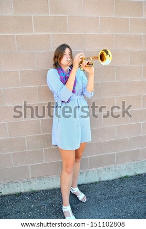 Female trumpet player with her horn outside.