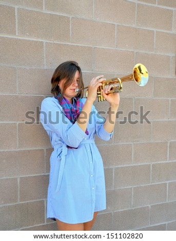 Female trumpet player with her horn outside.