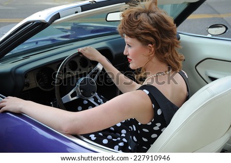 Female beauty fashion model sitting in her classic convertible car.