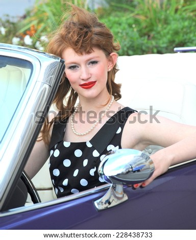 Female beauty sitting in her classic car outside.
