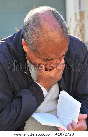 African american man reading a book outside.