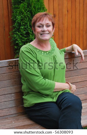 Mature female beauty sitting on her patio bench.