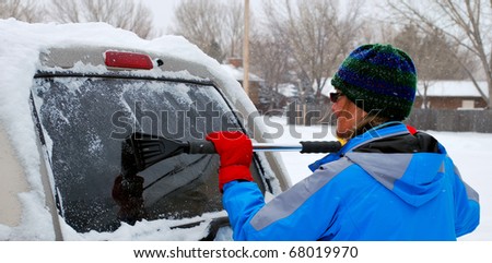 Woman cleaning snow off her suv.
