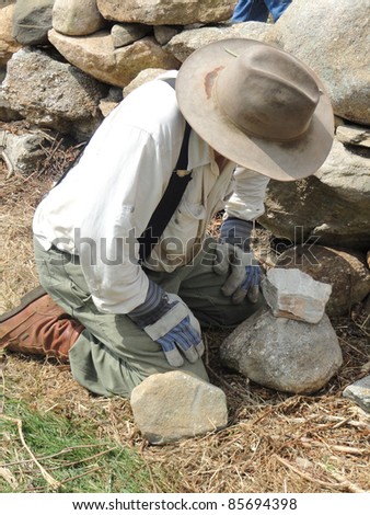 Land trust owner building a stone wall.