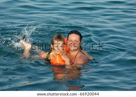 Family at sea. Mom and little girl floating in the sea.