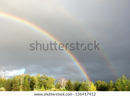 There are rainbow, cloudy sky and forest