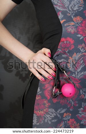 girl holding a pink ball gag. focus on hands with a gag