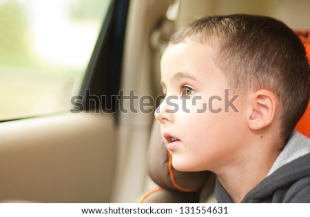 Curious little boy in the car watching the window sitting in safe chair