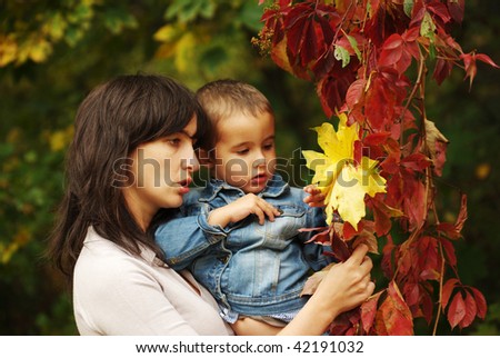 Beautiful woman and boy pick up yellow and red leaves
