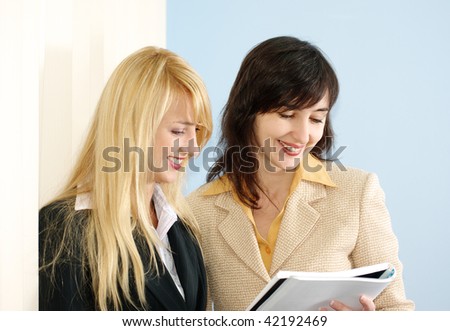 Blonde and brunette women on the meeting in the office reading the report