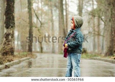 Little boy plays guitar in rainy park
