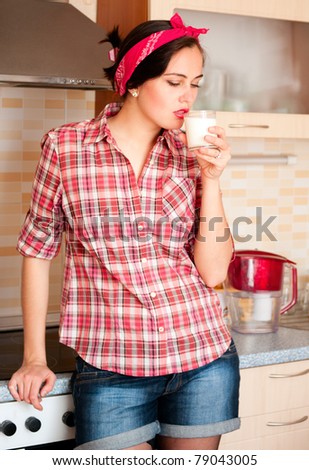 Sexy housewife in kerchief  drinks milk standing on the kitchen